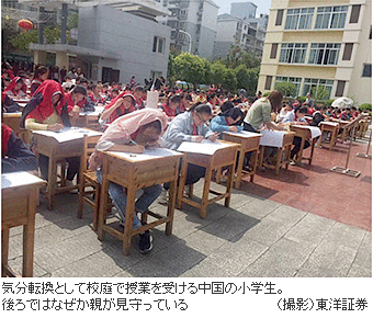 気分転換として校庭で授業を受ける中国の小学生。後ろではなぜか親が見守っている　（撮影）東洋証券
